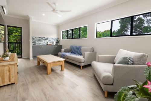 a living room with two couches and a table at Rainforest Escape with Pool & Mountain Views in Caravonica