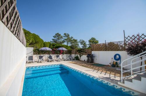 einen Pool mit Stühlen und Sonnenschirmen neben einem Gebäude in der Unterkunft Villa Granada in Almancil