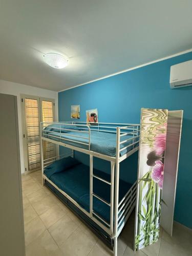 a room with two bunk beds and a blue wall at Bilocale zona spiaggia Home Salento com in Torre San Giovanni Ugento