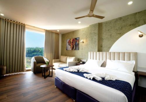 a hotel room with a bed and a couch and a window at River Bay Athirappilly in Athirappilly
