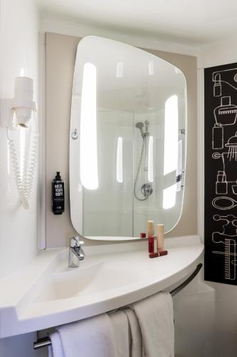 a bathroom with a sink with a mirror and towels at ibis Amsterdam Centre Stopera in Amsterdam