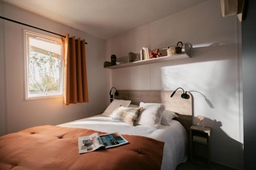 a bedroom with a bed with a book on it at Camping Le Walric in Saint-Valéry-sur-Somme