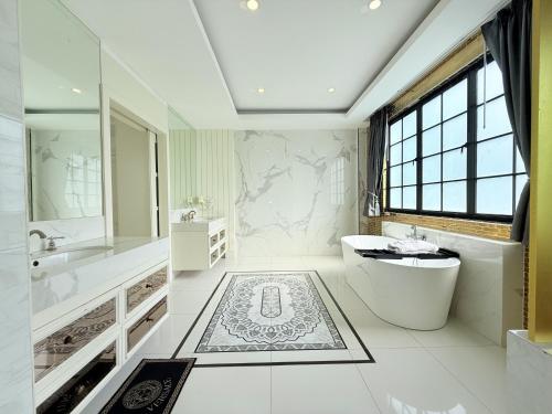 a bathroom with a tub and a toilet and a sink at Pool Villa Pattaya 5BD - Exquisite Pool Villa G in Nong Prue