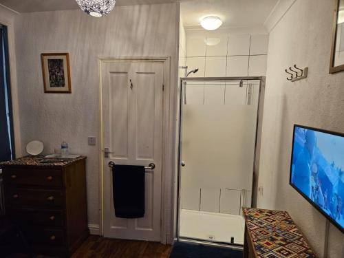 a bathroom with a shower stall and a television at East of Ipswich Bed and Breakfast - Private & Dorm Rooms Suffolk in Ipswich