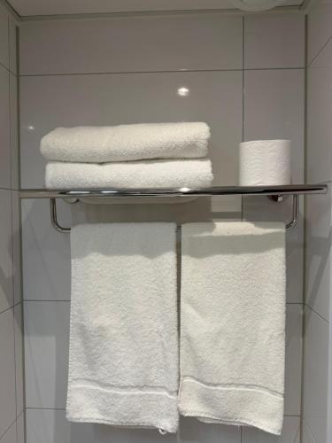 a towel rack with white towels on it in a bathroom at Hotel Zee en Duin in Katwijk