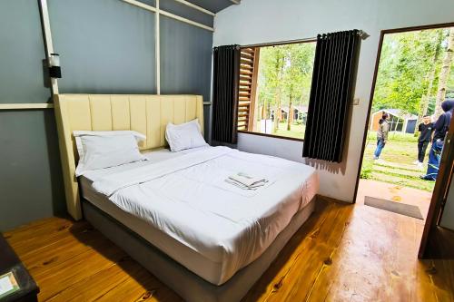 a bedroom with a large bed with a large window at Spekta Merbabu powered by Cocotel in Jlarem