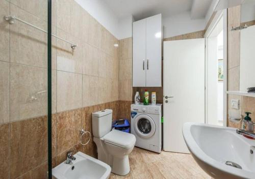 a bathroom with a toilet and a sink and a washing machine at The Beachfront Bliss by PS in Golem