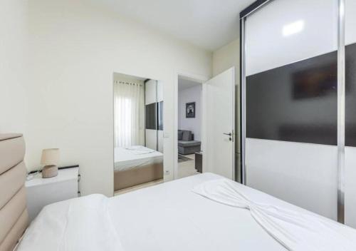 a white bedroom with a large white bed and a mirror at The Beachfront Bliss by PS in Golem