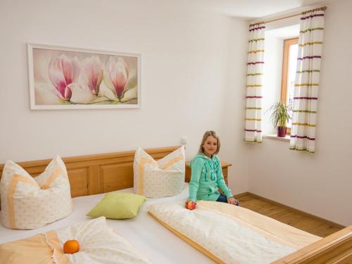 a little girl sitting on top of a bed at Ruhlander-Hof in Unterwössen