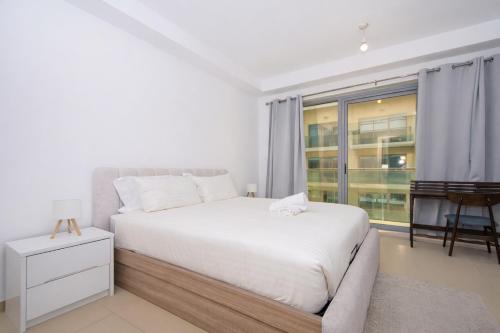 una camera da letto bianca con un letto e una finestra di Island Sands Studio a Ras al Khaimah