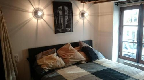1 dormitorio con cama con almohadas y ventana en The Pearl of Marais en París
