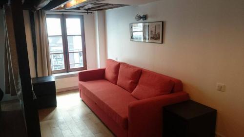 a red couch in a living room with a window at The Pearl of Marais in Paris