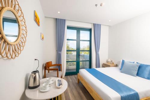 a bedroom with a bed and a table and a mirror at Cybade Hôtel in Phú Quốc