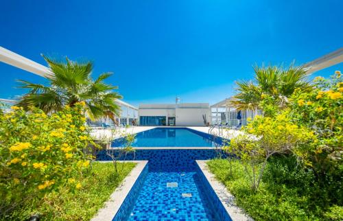una piscina di fronte a un edificio con palme di Island Sands Studio a Ras al Khaimah