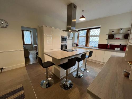 a kitchen with a island with bar stools at Ashley House Contemporary 4 Bedroom Stay for 13 in Inverness