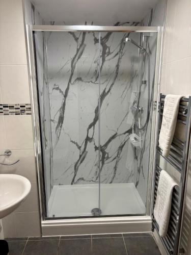 a shower with a glass door in a bathroom at Marine Apartment in Aberystwyth