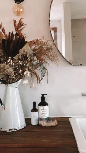 a bathroom counter with two bottles of soap and a mirror at Luxe Country Cabin - The Ateliers Cottage