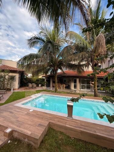 a swimming pool in front of a house with a palm tree at Casalapraia in Caraguatatuba