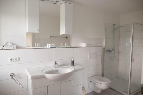 a white bathroom with a sink and a toilet at Hotel-Restaurant Faehr-Cafe in Niesgrau