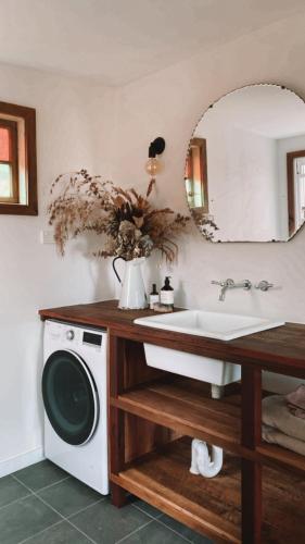 a bathroom with a sink and a washing machine at Luxe Country Cabin - The Ateliers Cottage