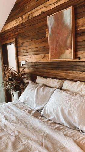 a bed with a wooden wall with a picture above it at Luxe Country Cabin - The Ateliers Cottage