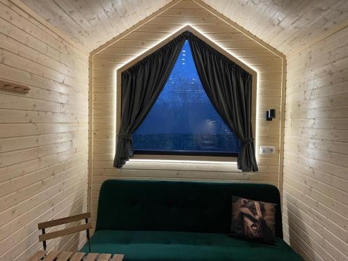 a green couch in a room with a window at Badgers Hollow by Tiny Away in Whitchurch