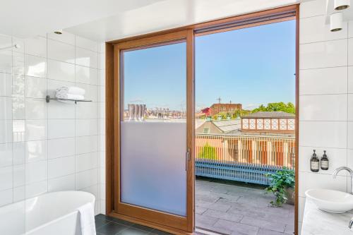 a bathroom with a tub and a glass door at Backstage Hotel Stockholm in Stockholm