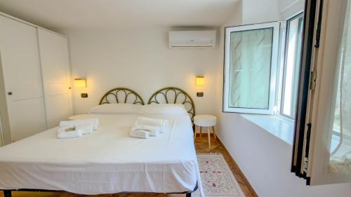 a white bedroom with a bed and a window at Casa CarMa - Relax & Comfort a Cala Gonone in Cala Gonone