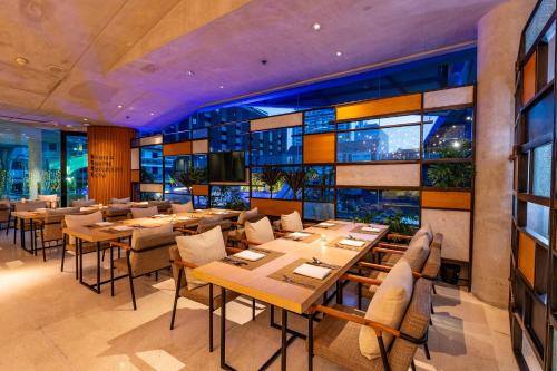 a restaurant with tables and chairs and windows at LiT BANGKOK Hotel in Bangkok