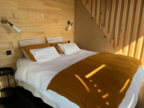 a bedroom with a large bed with a wooden wall at Le séchoir de Valadon in Aillas