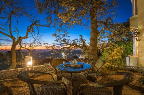 a table and chairs on a patio with a view at Tripli Hotels Le Royale, Shimla in Shimla