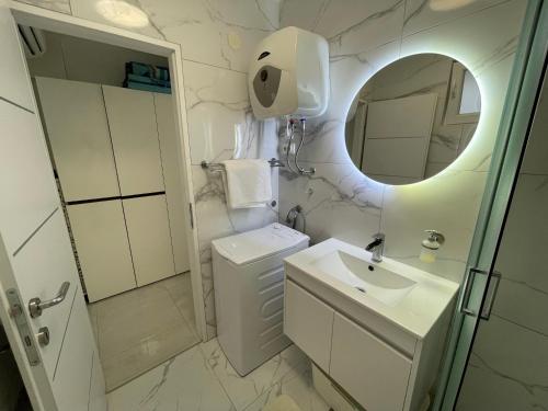 a white bathroom with a sink and a mirror at Studio apartman Sunset cove in Stinica