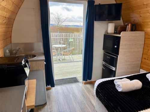 a room with a bed and a kitchen with a patio at The Midi Pod in Aberystwyth