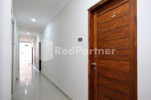 a corridor with a wooden door in a house at Hotel Andono near YIA Mitra RedDoorz in Yogyakarta