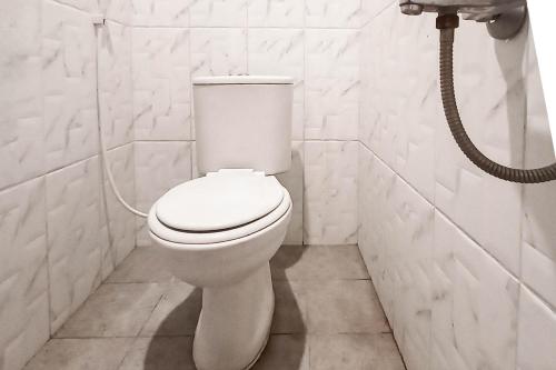 a white toilet in a bathroom with a shower at RedDoorz at Deluxe Hotel near Terminal Purabaya Bungurasih in Sidoarjo