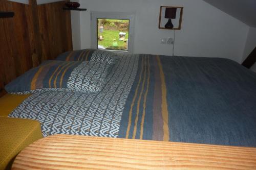 a bedroom with a bed with a blue blanket and a window at Gite D'étape de roslaye in Gourin