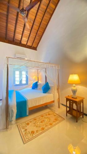 a bedroom with a bed and a table with a lamp at Mishthana Canal Resort in Bentota