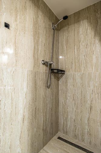 a shower in a bathroom with a stone wall at K-plus penzión in Štúrovo