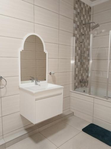 a white bathroom with a sink and a shower at Indawo Guesthouse in Bloemfontein