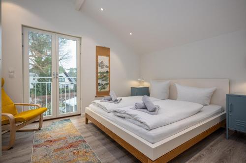 a bedroom with a large white bed and a yellow chair at Chalet Wacholder in Dierhagen