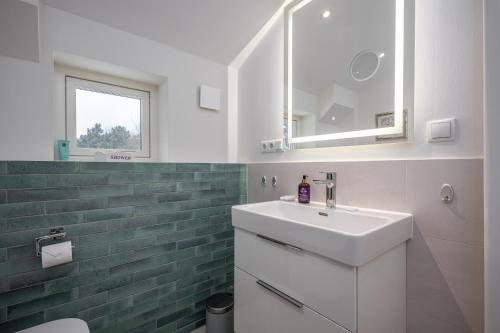 a white bathroom with a sink and a mirror at Chalet Wacholder in Dierhagen