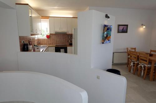 a kitchen and dining room with white cabinets and a table at Villa H - Kamari Village in Kastraki