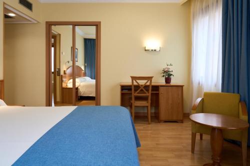 a hotel room with a bed and a table and a desk at II Castillas Madrid in Madrid