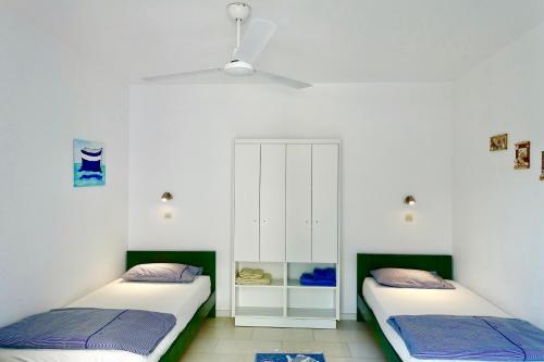 a bedroom with two beds and a cabinet at Villa H - Kamari Village in Kastraki