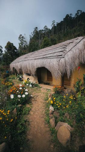 a building with a grass roof with flowers in front at EKa Forest in Vattavada