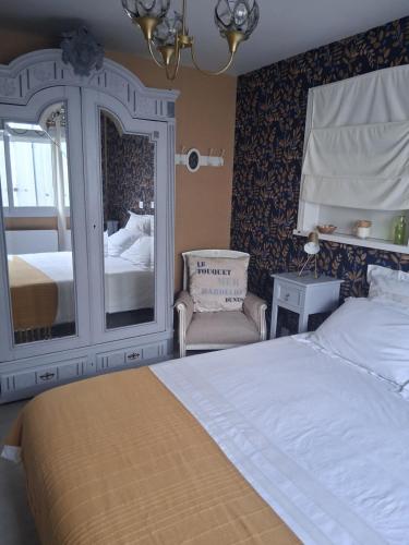 a bedroom with a bed and a mirror and a chair at La petite maison in Saint-Martin-lez-Tatinghem