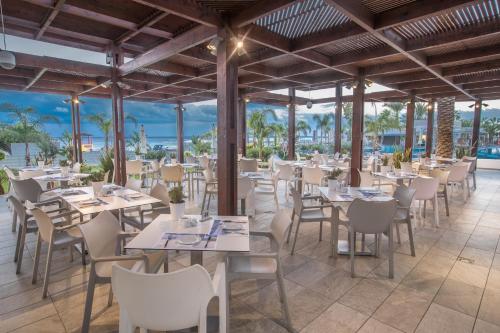 a restaurant on the beach with tables and chairs at Vassos Nissi Plage Hotel & Spa in Ayia Napa