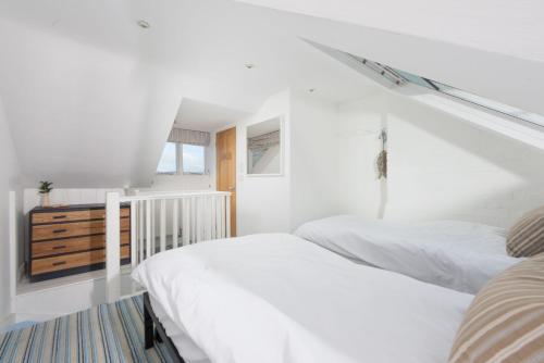 a white bedroom with two beds and a staircase at Walters on The Digey - 100m to beach - pets allowed in St Ives