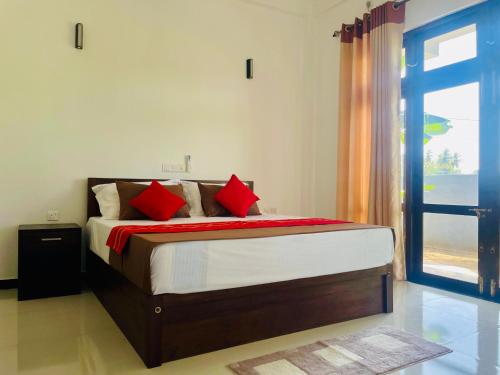 a bedroom with a bed with red pillows and a window at Ayubowan Yala in Tissamaharama