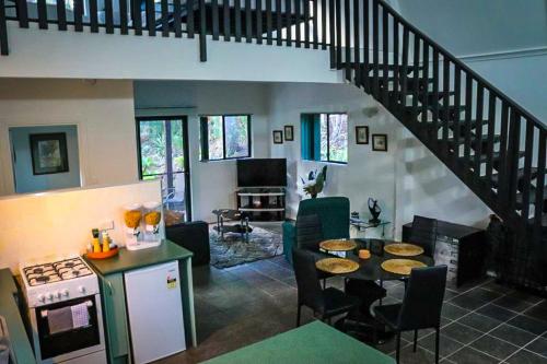 a living room with a staircase and a kitchen with a table at GREEN TREES CHALET Australia Zoo close by in Landsborough